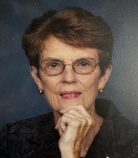 Elderly woman with glasses and short brown hair.