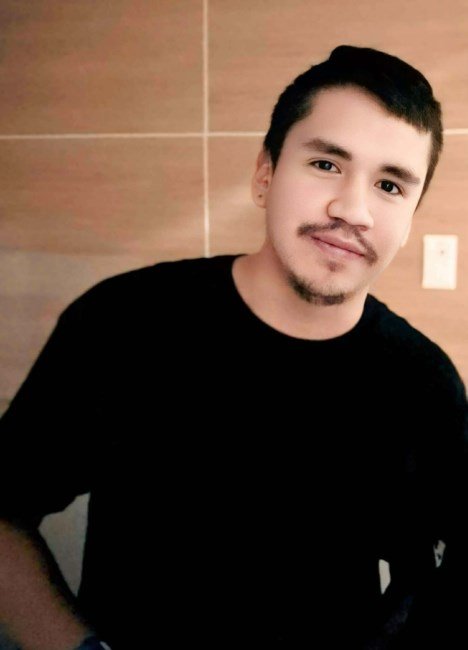 Person in a black shirt smiling indoors.
