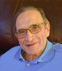 Smiling elderly man wearing glasses and a blue shirt.