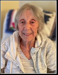 Elderly woman smiling in casual clothing indoors.