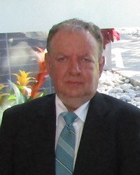 Man in suit with turquoise tie outdoors.