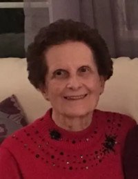 Smiling woman in red sweater seated indoors.