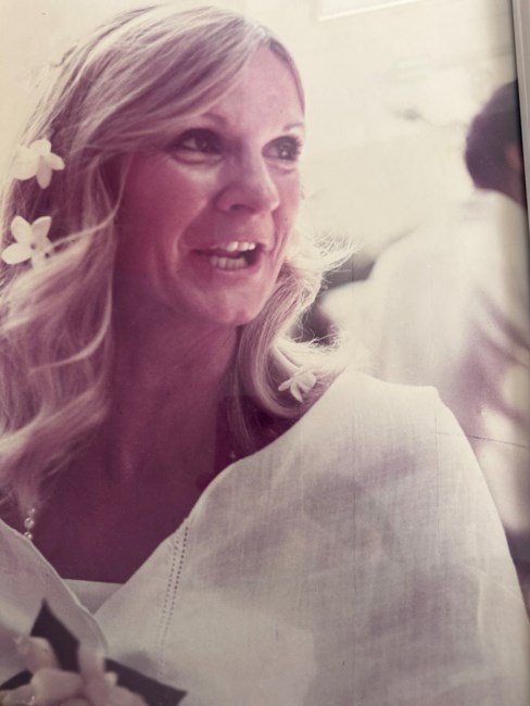 Smiling woman with flowers in hair, sepia-toned photo.