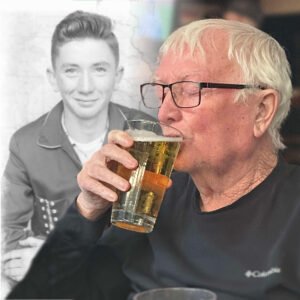 Elderly man drinks beer, young man photo in background.