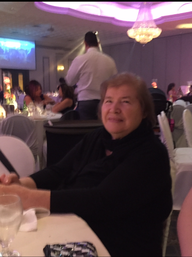 PANAGIOTOPOULOS, Ourania Panagiotopoulos Elderly woman smiling at event with purple lighting.