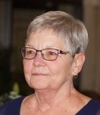 Elderly woman with short gray hair and glasses.