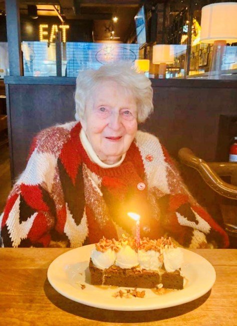 Smiling senior woman with birthday cake in restaurant.