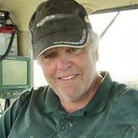 Smiling person in a cap inside a vehicle.