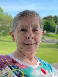 Elderly woman smiling outdoors in a colorful shirt