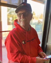 Smiling man in red hoodie and cap indoors