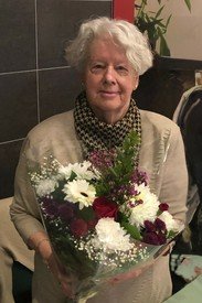 Elderly woman holding a bouquet of flowers.