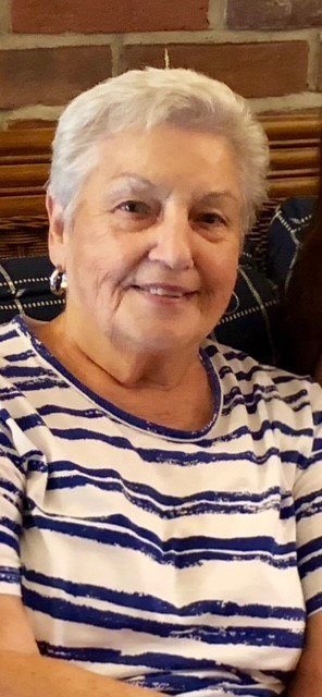 Smiling woman in striped shirt sitting indoors.