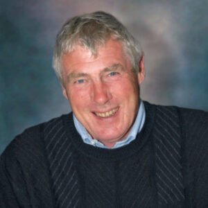 Smiling older man in dark sweater portrait.