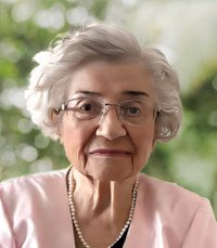 Elderly woman wearing glasses and a pink blouse.