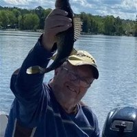 Man holding a fish by a lake