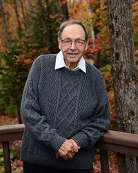 Man in sweater on forest deck in autumn.