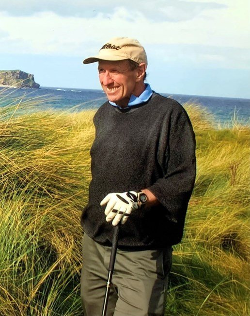 Man golfing near ocean on a windy day.