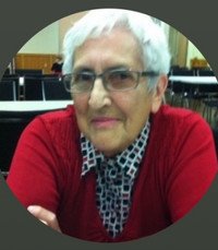 Elderly woman sitting and smiling indoors.