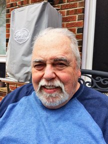 Smiling man sitting outside on a chair.