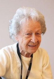 Smiling elderly woman with white hair and sweater.