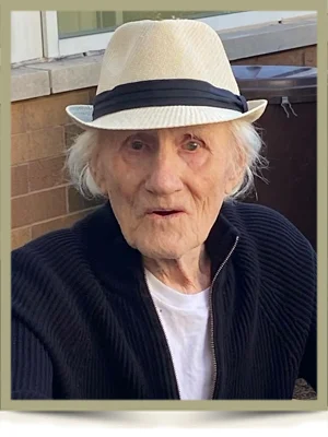 Elderly person wearing a white hat outdoors.