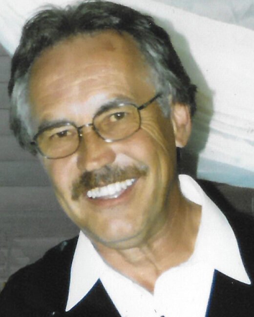 Smiling man with glasses and mustache.