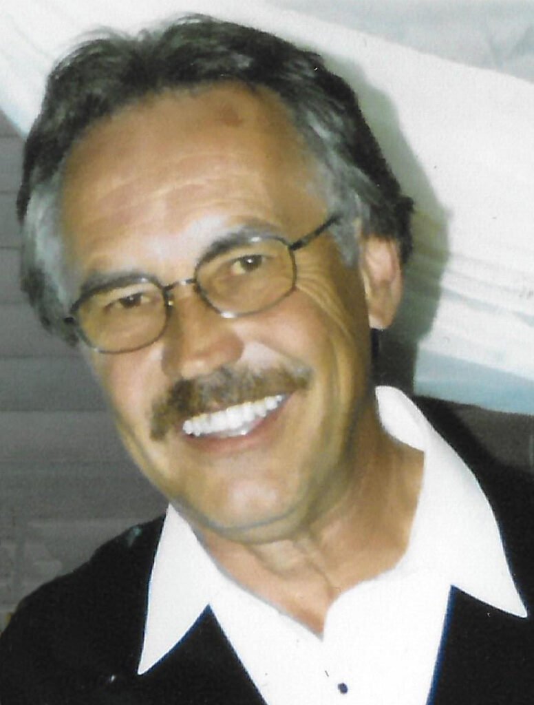 Smiling man with glasses and mustache.
