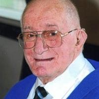 Elderly man smiling with glasses and tie.