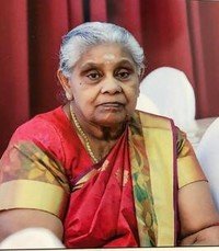 Elderly woman in traditional attire, seated and smiling
