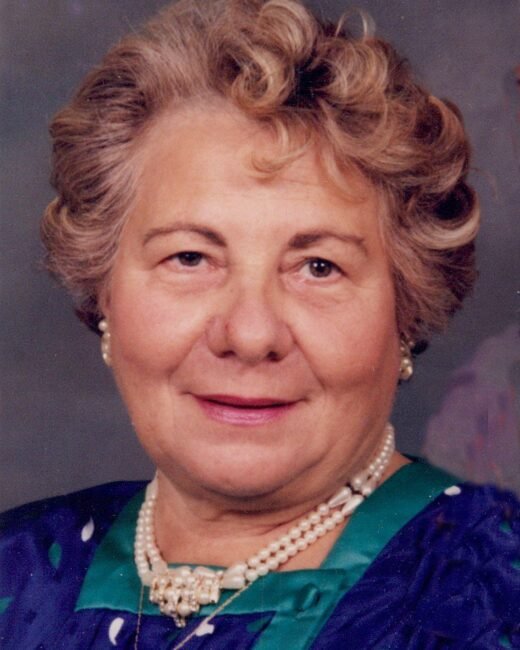 Elderly woman wearing pearls, smiling.