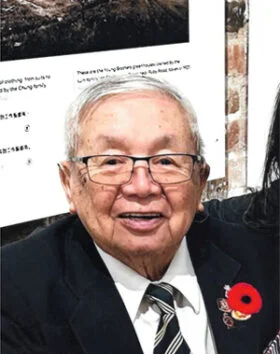 Elderly man in suit with poppy flower pin.