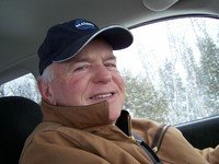 Smiling person in car wearing a black cap.
