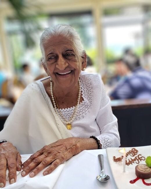 Smiling elderly woman enjoys dessert at a restaurant.