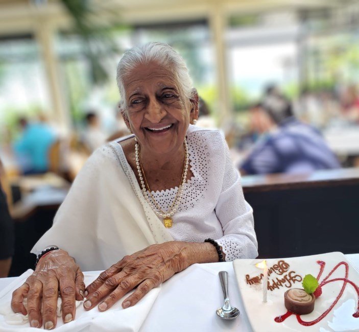 Smiling elderly woman enjoys dessert at a restaurant.