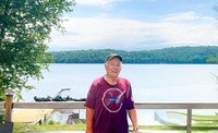 Person in hat by a scenic lake view.