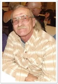 Smiling man sitting at a table with glasses.