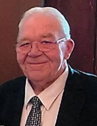 Older gentleman in a suit smiling.