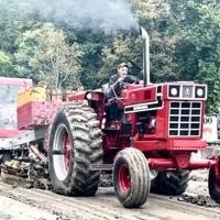 Red tractor pulling heavy load on dirt path.