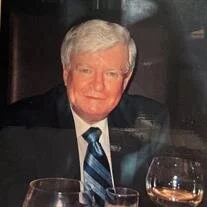 Elderly man in suit at dining table with wine.