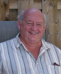 Smiling man sitting on a chair outdoors.