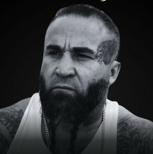 Tattooed man with beard and white tank top