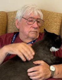 Elderly man petting a black and white cat.