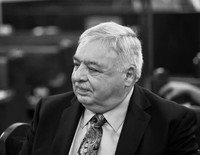 Elderly man in suit, seated at an event.