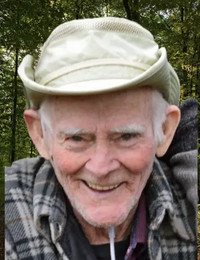 Elderly man smiling outdoors with hat and plaid shirt.