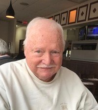Smiling elderly man in a cozy restaurant setting.