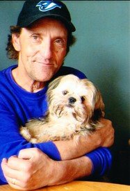 Person holding a small dog, smiling.