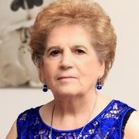 Elderly woman in a blue dress, serious expression.