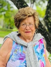 Elderly woman outdoors in floral dress and sweater.