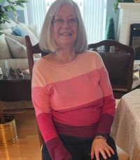 Smiling woman in colorful sweater sitting indoors.
