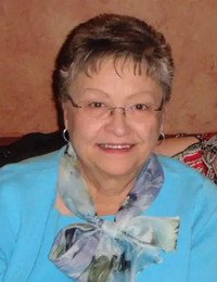 Smiling elderly woman wearing blue shirt and scarf.